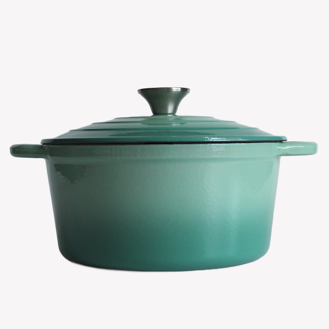 Grön gjutjärnsgryta med lock. Gjutjärnsgrytan står på en vit bakgrund. Den har en blank emaljerad yta och ett lock med en silverfärgad knopp.