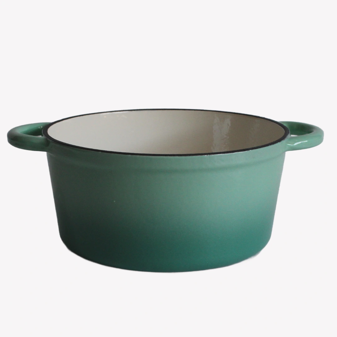 Grön gjutjärnsgryta utan lock. Grytan har en blank emaljerad utsida och en vit emaljerad insida. Grytan står på en vit bakgrund.