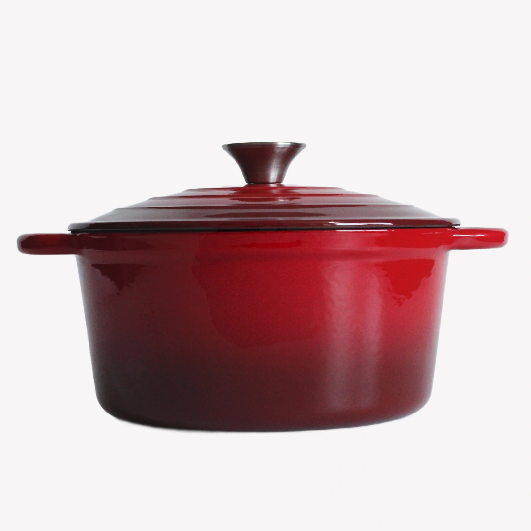 Röd gjutjärnsgryta med lock. Gjutjärnsgrytan står på en vit bakgrund. Den har en blank emaljerad yta och ett lock med en silverfärgad knopp.