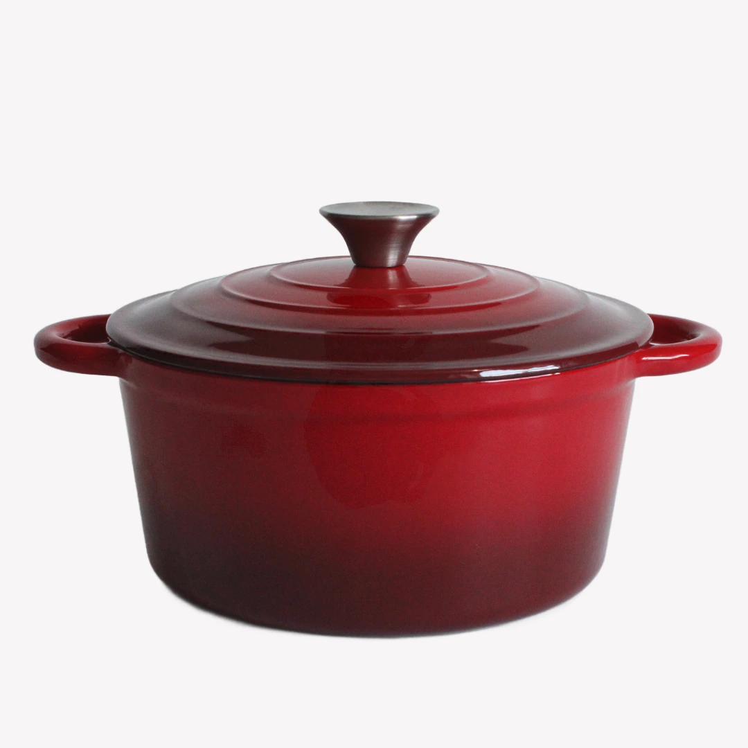 Röd gjutjärnsgryta med lock. Gjutjärnsgrytan står på en vit bakgrund. Den har en blank emaljerad yta och ett lock med en silverfärgad knopp.