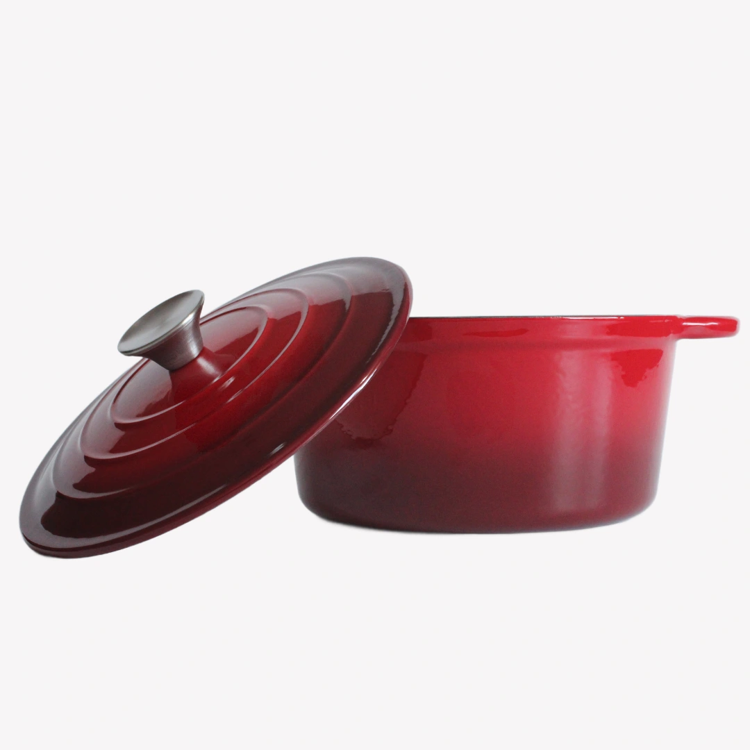 En röd gjutjärnsgryta med locket avtaget. Locket lutar mot grytan, Båda står på en vit bakgrund.