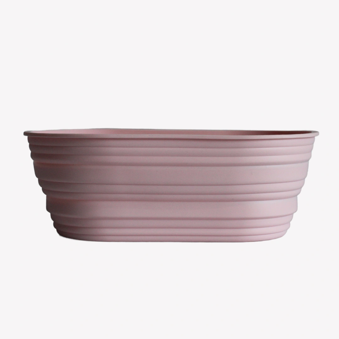 jaskorg_oval_silikon_rosa En oval jäskorg i rosa silikon. Jäskorgen har en veckad yta och står på en vit bakgrund.