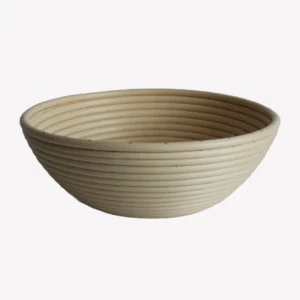 En rund jäskorg i beige plast med en veckad yta. Jäskorgen står på en vit bakgrund.