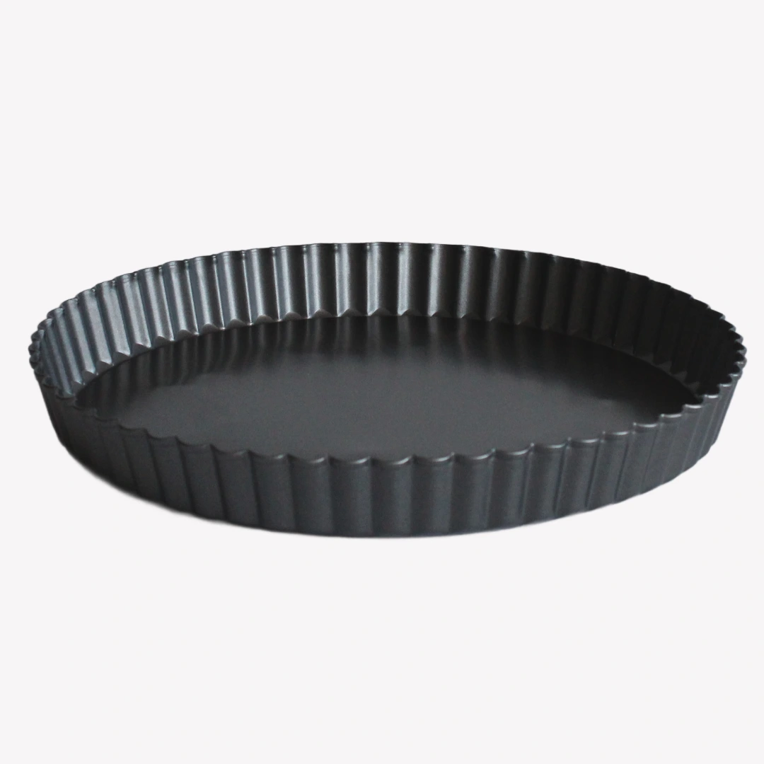 Svart pajform med räfflade kanter och non-stick beläggning. Pajformen står på en vit bakgrund.