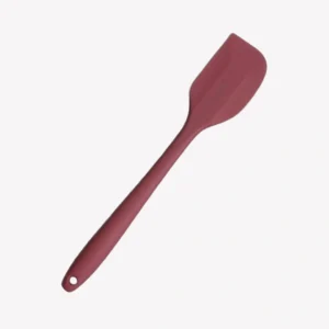 En rosa slickepott i silikon med långt handtag och ett hål för upphängning. Slickepotten ligger snett på en vit bakgrund.