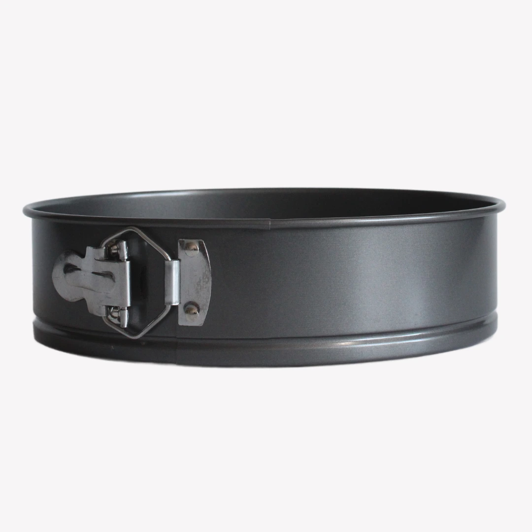 springform_24cm Svart springform 24 cm med non-stick beläggning, löstagbar botten och metallspänne. Springformen ligger på en vit bakgrund