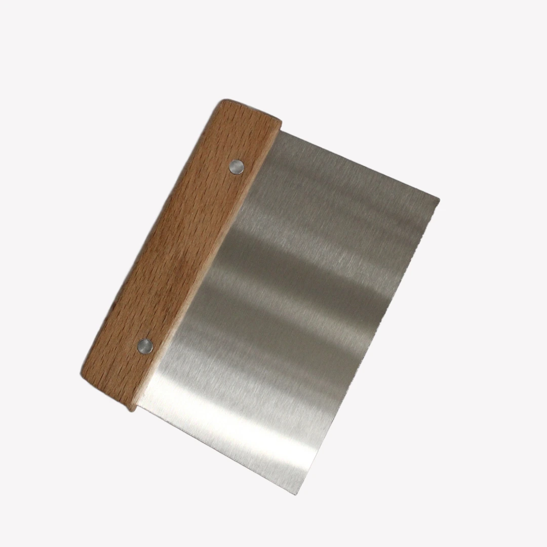 Degskrapa_tra En degskrapa i rostfritt stål med ett trähandtag. Degskrapan ligger på en vit bakgrund.