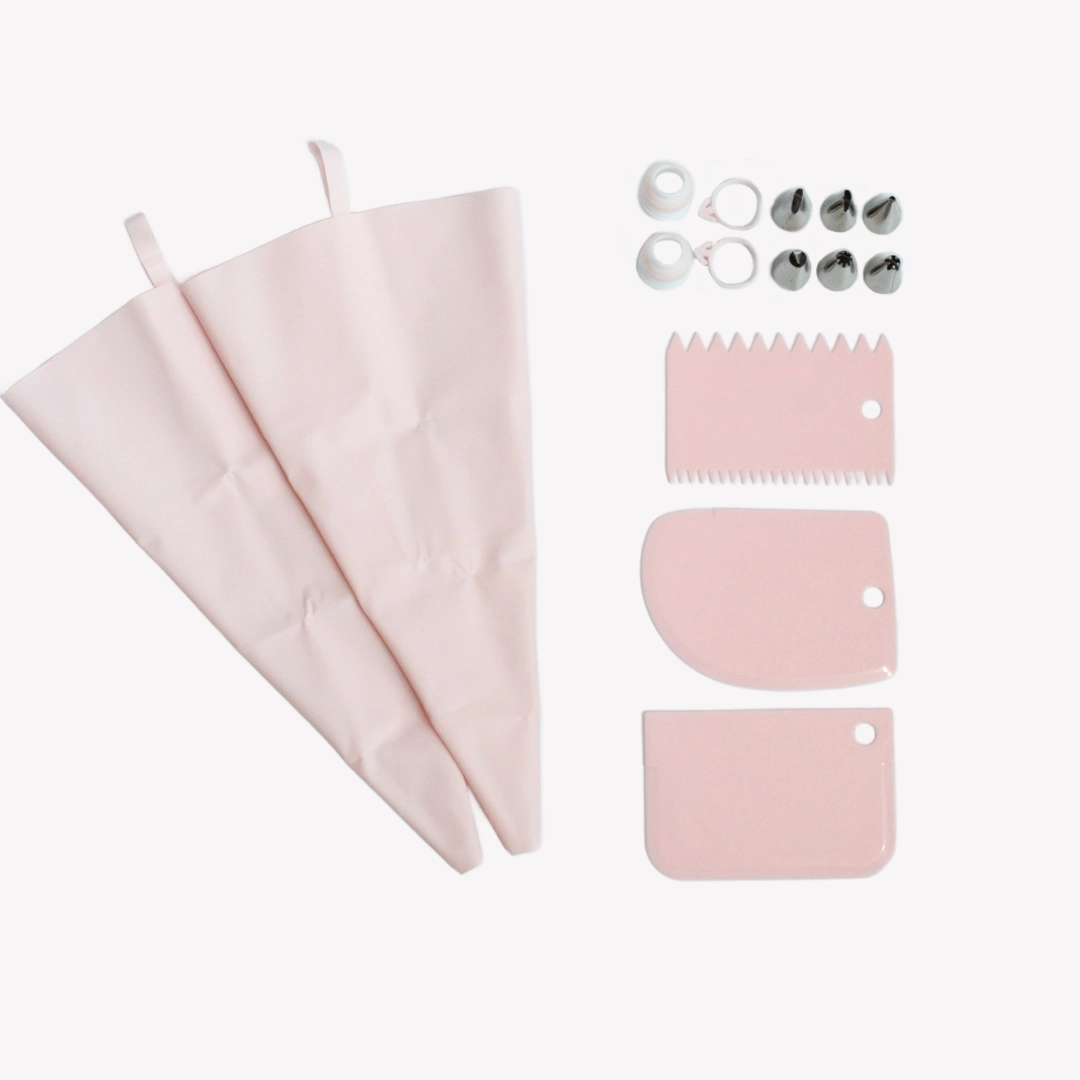 Spritsset_silikon_rosa Ett spritsset i ljusrosa färg med två spritspåsar, sex tyllar, tre skrapor och två silikonband. Setet ligger upplagt på en vit bakgrund.