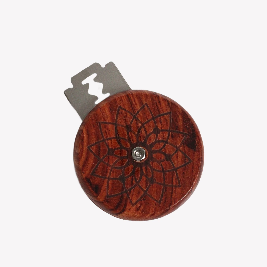 En rund snittkniv i trä med ett ingraverat mönster, designad för att skära mönster i bröd. Kniven har ett vasst metallblad och ligger på en vit bakgrund.