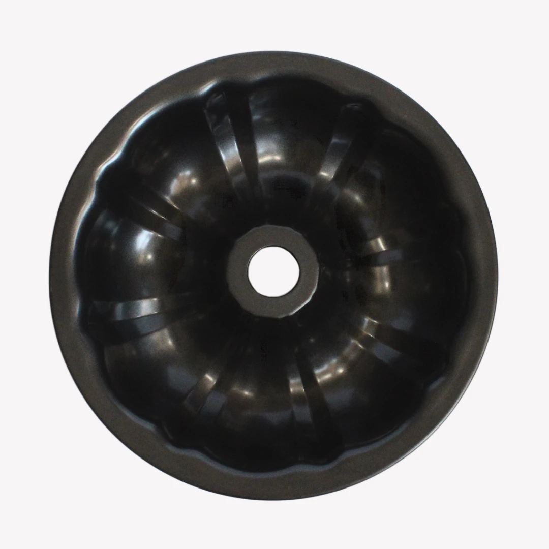 sockerkasform_24cm_3 En svart sockerkaksform i metall med vågig kant och ett hål i mitten. Formen står på en vit bakgrund.