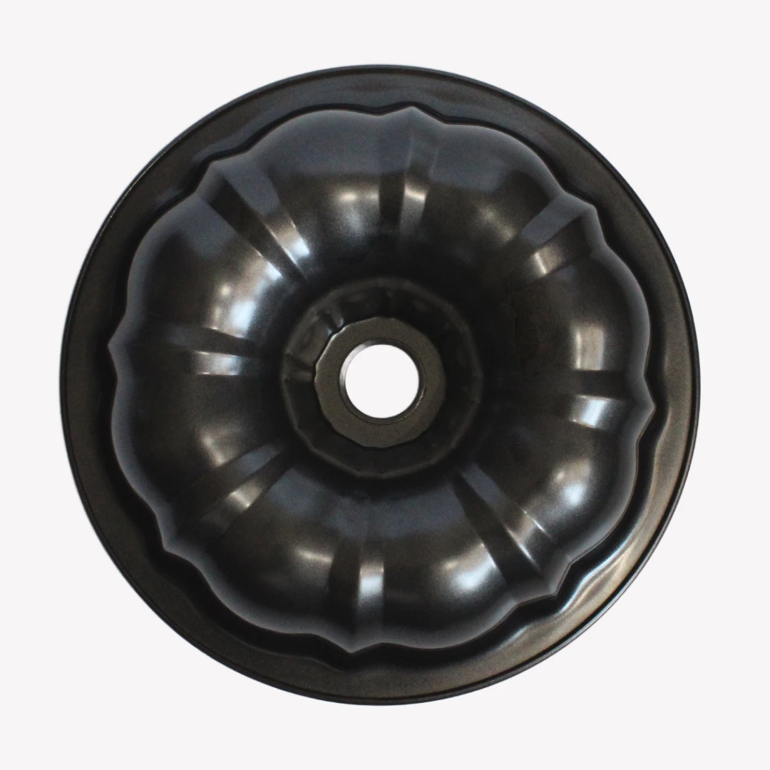 sockerkasform_24cm_4 En svart sockerkaksform i metall med vågig kant och ett hål i mitten. Formen står på en vit bakgrund.